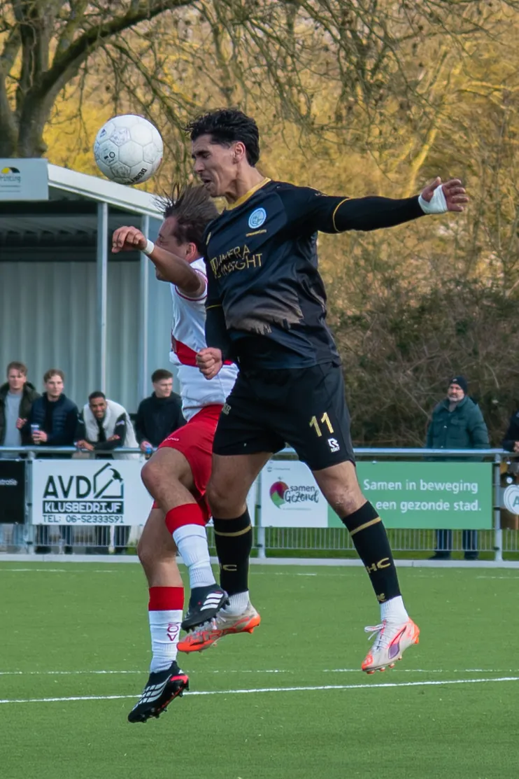 Twee spelers in duel om een kopbal tijdens een voetbalwedstrijd