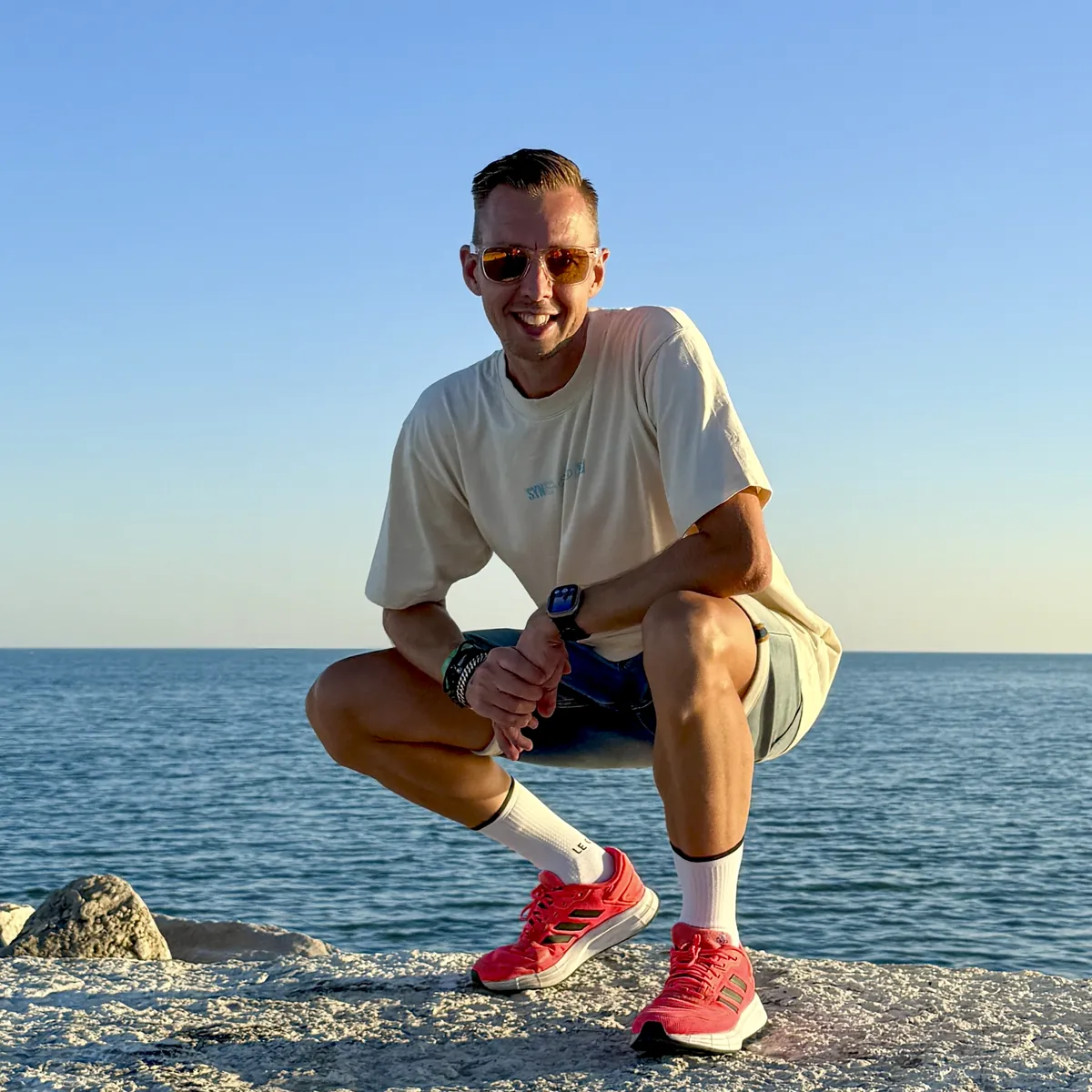 Portrait of Erwin Bierens, photographer and founder of Studio Sjas Patat, crouching on the rocks by the sea