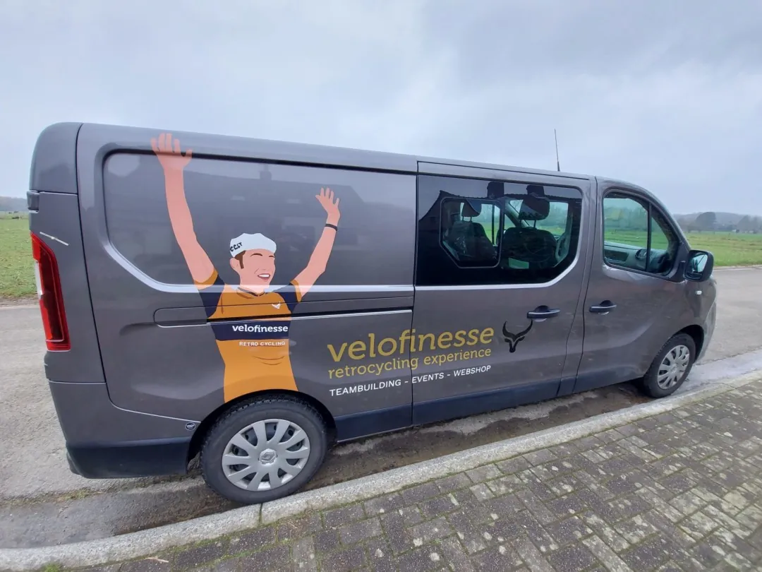 Belettering van de Velofinesse-bus met een getekende renner die beide armen opsteekt